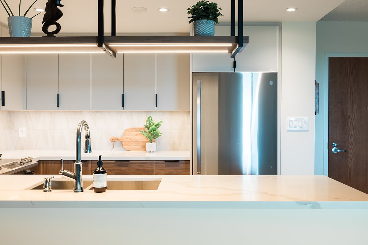 Under mount kitchen sink with stainless steel faucet in GTA condo renovation with hanging light fixture