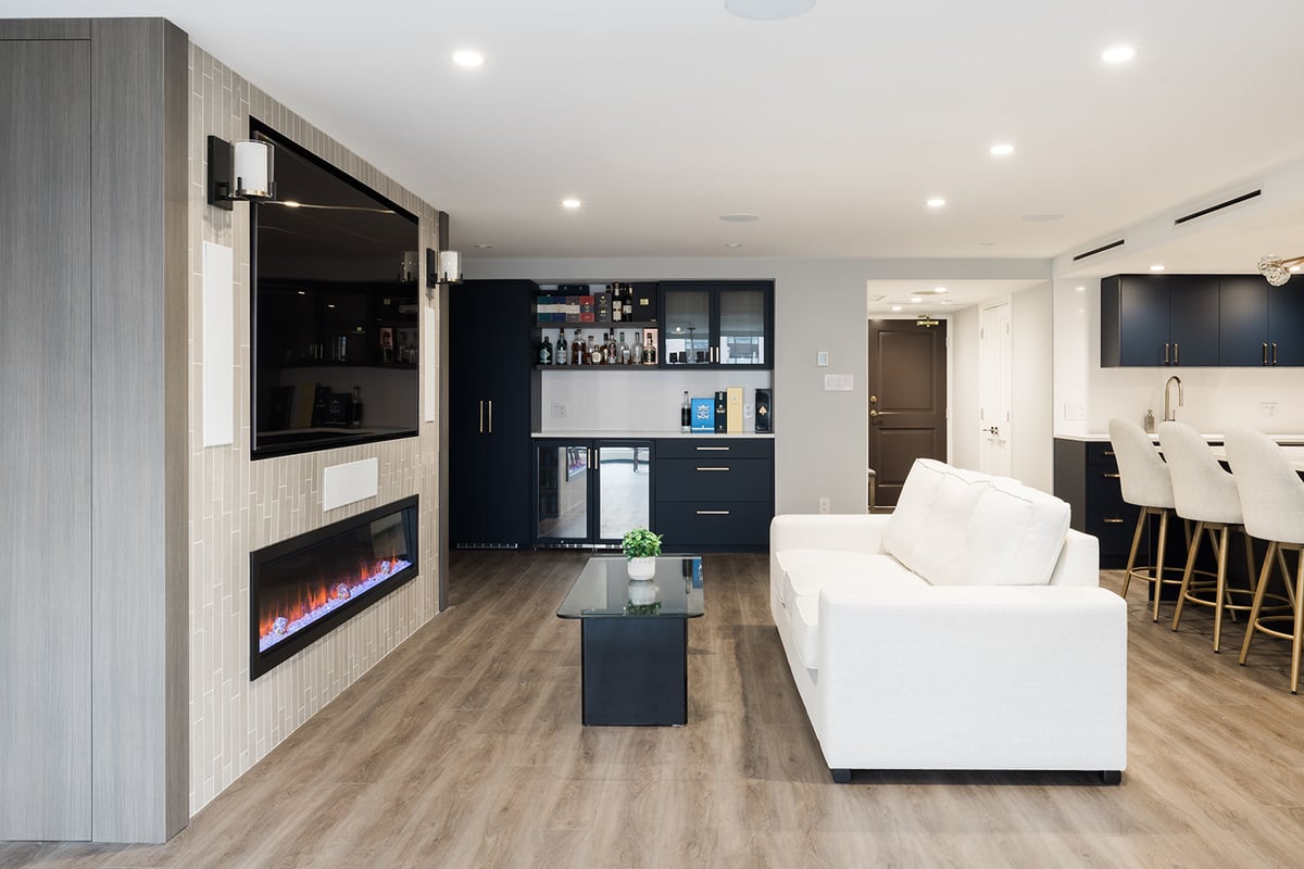 View of custom fireplace in living room in downtown Toronto condo renovation with view of beverage station and kitchen by Golden Bee Condos