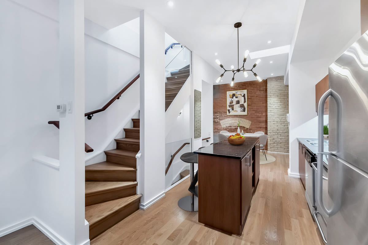 Toronto condo renovation with island beneath light fixture and stairs to second-story