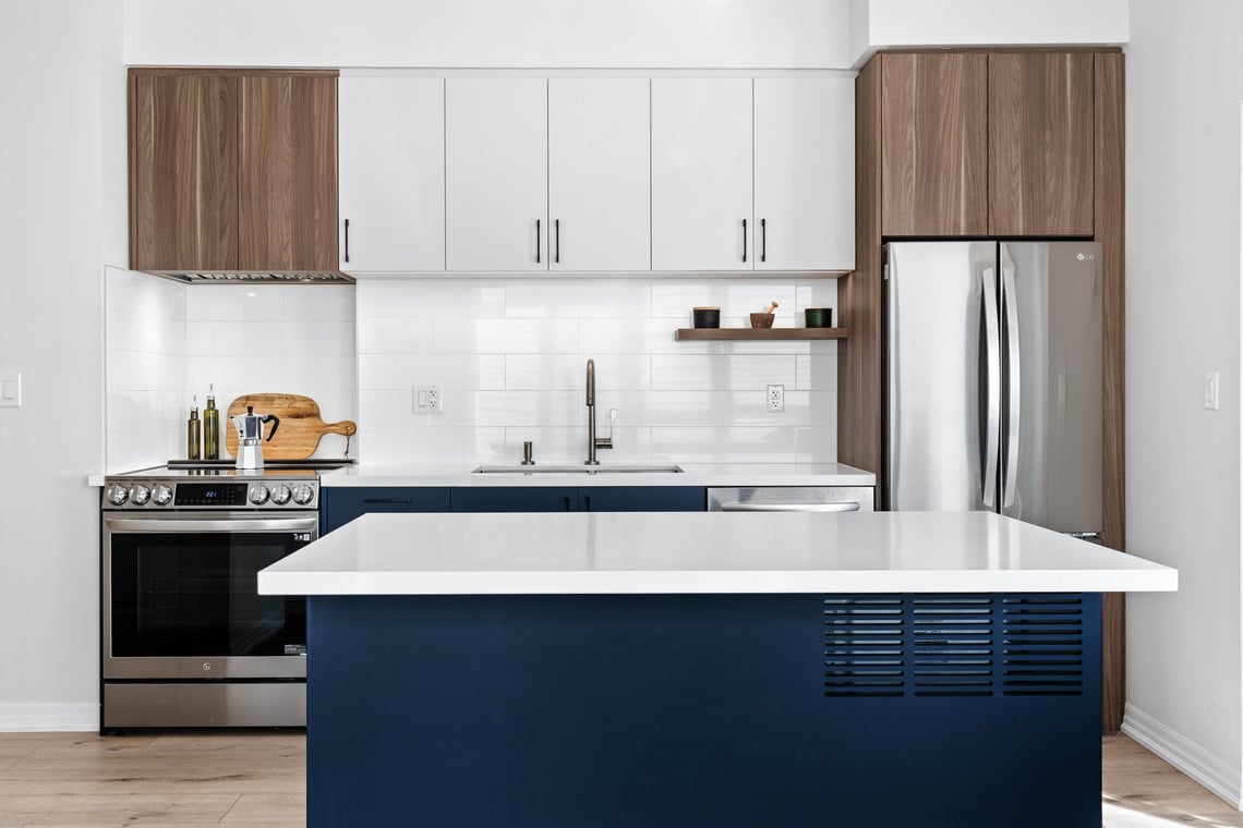 condo kitchen renovation in toronto with blue cabinets on island and white tiled backsplash (1)