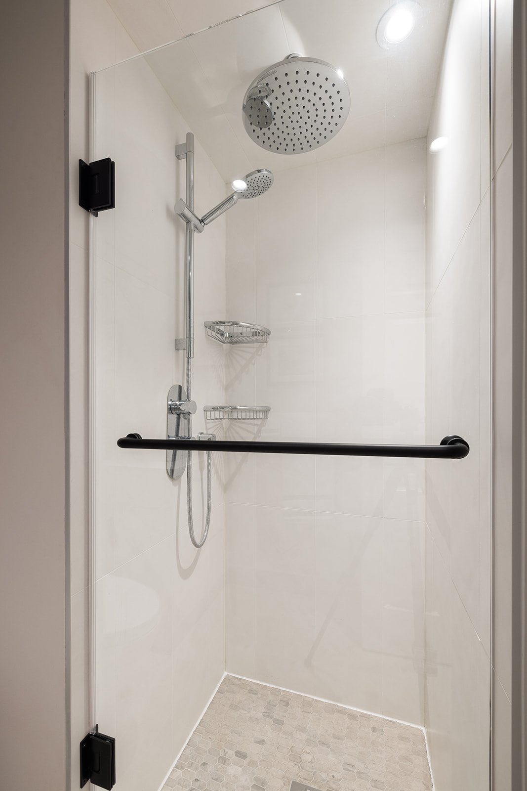 Glass shower door with stainless steel shower fixtures in Toronto condo bathroom renovation