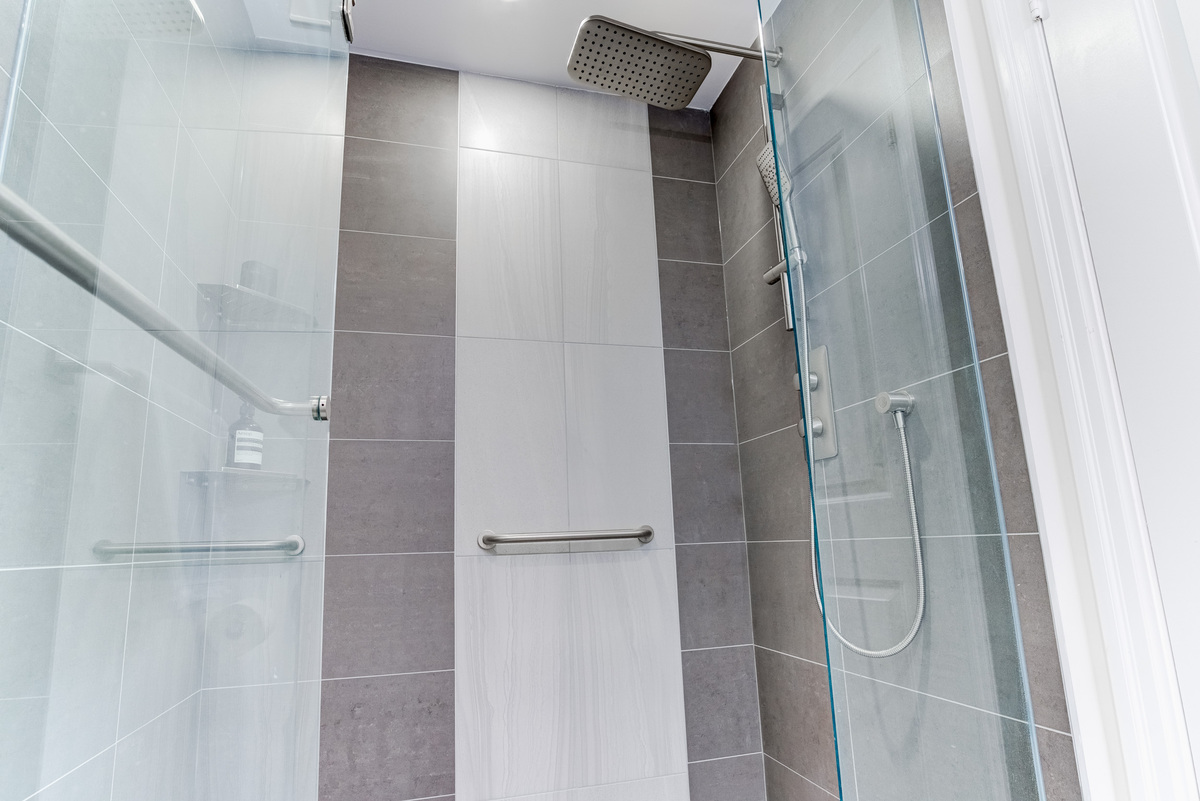 Glass doors on shower with built-in grab bars in Toronto condo bathroom renovation by Golden Bee Condos
