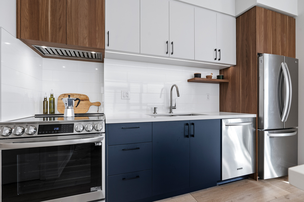 Wood, blue, and white cabinetry in Toronto with white backsplash by Golden Bee Condos 