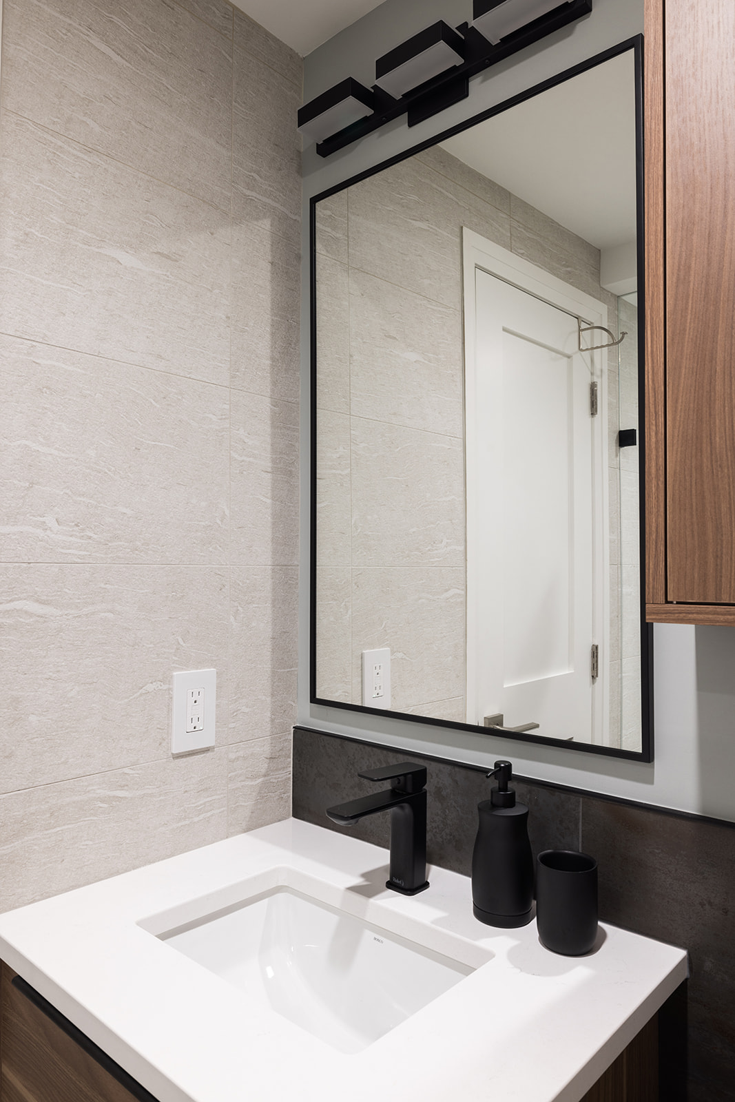 Mirror and sink with black faucet fixture in luxury condo bathroom renovation in downtown Toronto