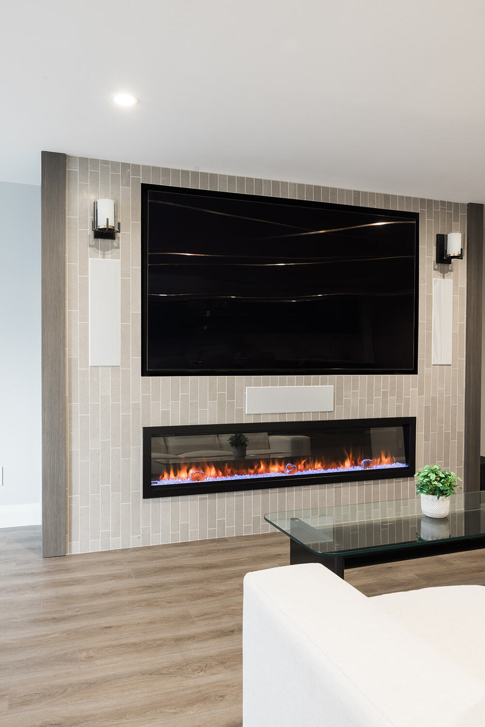 View of custom fireplace with mounted TV above in living room in downtown Toronto condo renovation with light sconces