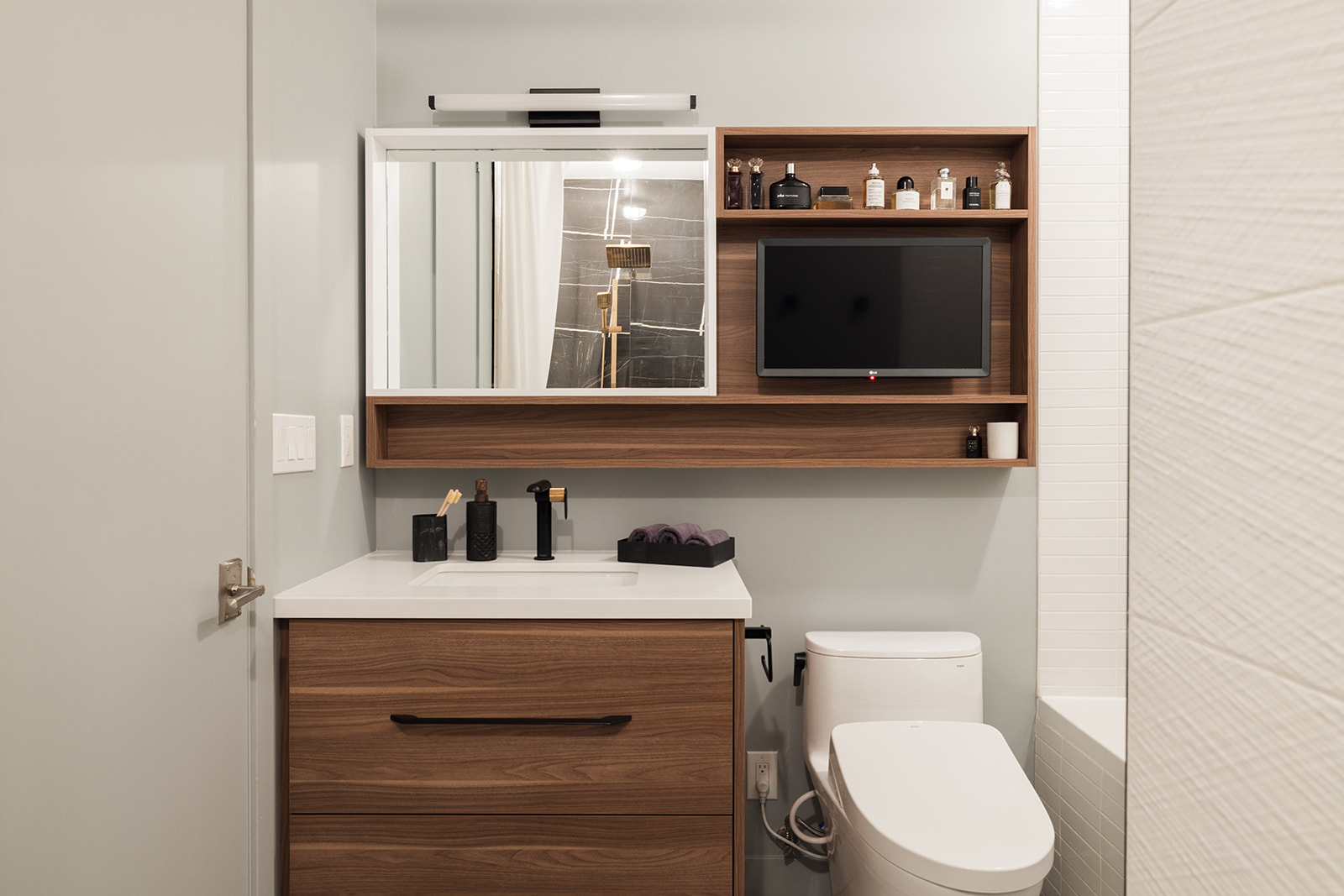 Built-in wall shelf and small TV above toilet in Toronto condo bathroom renovation